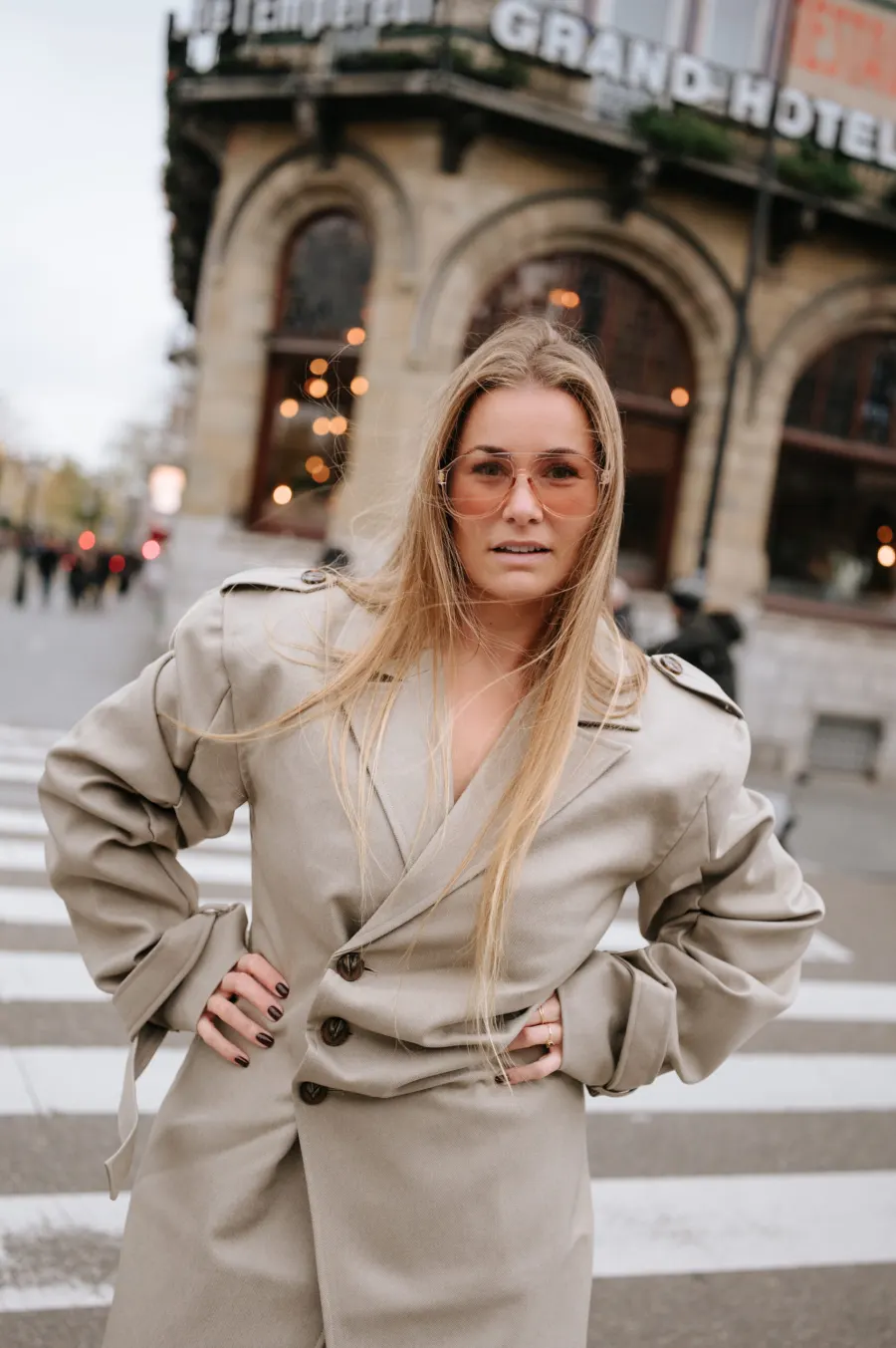 Clenda Moen, lachend op straat in een lange beige jas